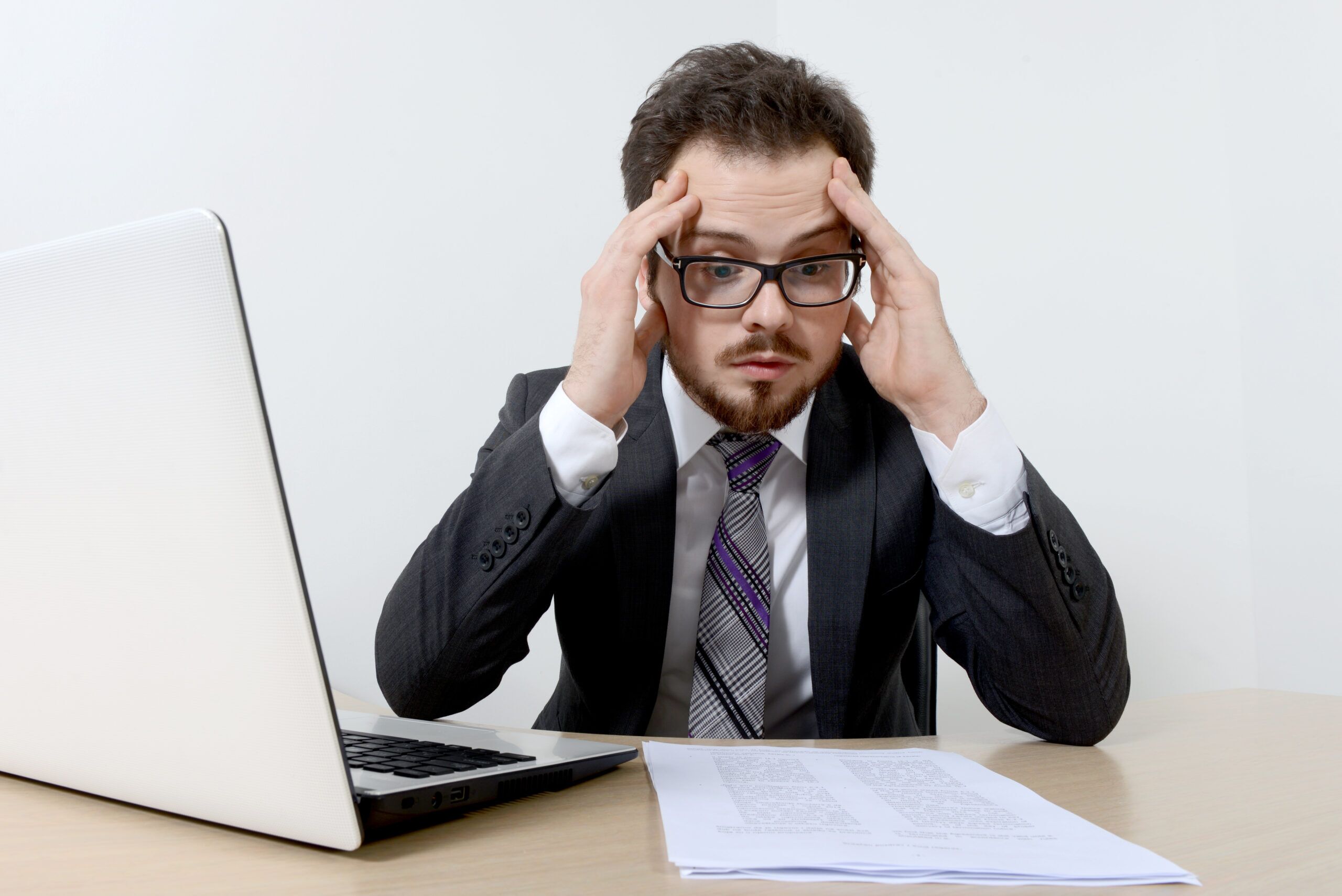 Worried young businessman with laptop and documents